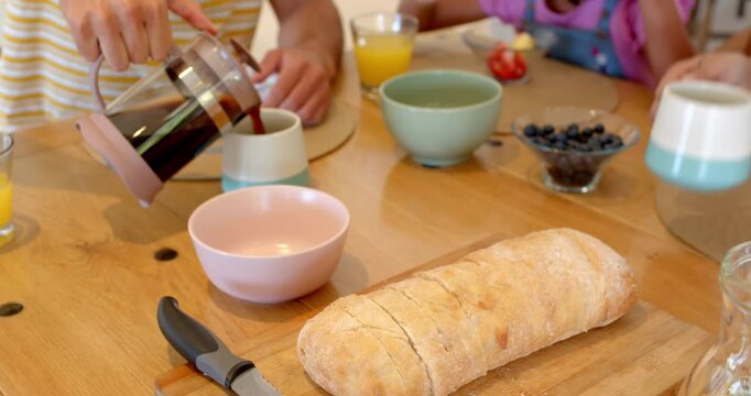 Family enjoying breakfast together, pouring coffee and sharing fresh fruit