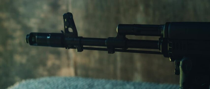 Closeup view of tactical rifle muzzle emits flash and smoke during firing at outdoor shooting range bench
