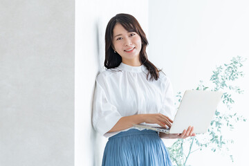 パソコンを持ちカメラ目線の若い日本人女性