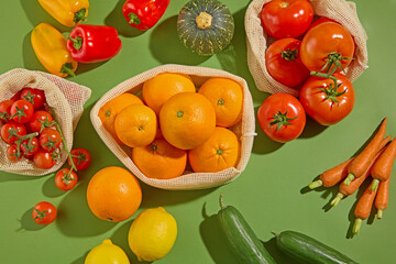 Colorful fresh vegetables including orange, tomatoes, and bell peppers are artfully arranged on a warm green surface, creating a healthy garden-inspired layout. Top shot, advertising photo