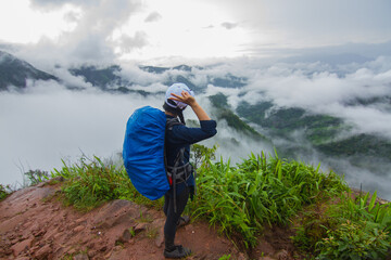 The woman climber is on the mountain with a cloud-covered view in the rainy season.