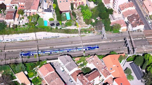 Drone view of blue train entering tunnel at 5 way railway in Marseille, France