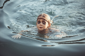 Young Tribal Boy Swimming In Lake Surrounded By Wilderness 