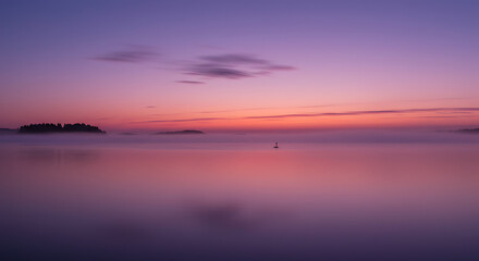 Fototapeta premium Serene Pink and Purple Sunrise over Foggy Lake with Island Silhouette