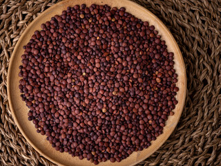 Organic uncooked seeds dark red brown lentils.