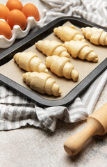 Freshly made croissants resting on baking sheet await oven's warm embrace