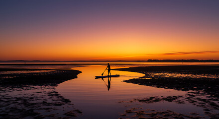 Stunning Sunset Silhouette of Paddleboarder on Calm Coastal Waters