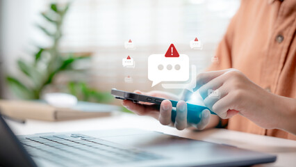 Close-up hand holding smartphone with spam alert icon popping up, concept of online scam warning, phishing message, cybersecurity, and mobile security notification.