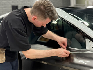Car wrapping, detailing, tuning and styling. Detailer smoothes PPF. A car wrapping specialist...