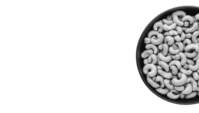 A black bowl overflowing with pale, roasted cashews, viewed from directly above against a stark black background