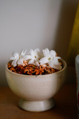 Ceramic bowl filled with dried and fresh jasmine flowers for aroma therapy