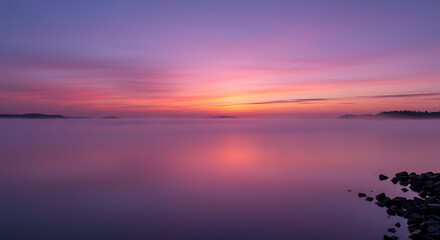 Fototapeta premium Serene Pink and Purple Sunrise over Misty Lake with Rocks