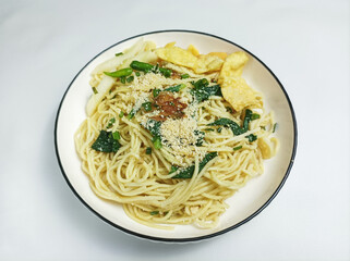 Mie Pangsit or Mie Ayam Pangsit. Noodles in a plate that are popular in Indonesia with minced chicken topping, green mustard greens. isolated on gray background