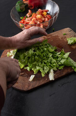 Hand slicing fresh green lettuce to prepare a healthy, crisp salad with vibrant ingredients in a...