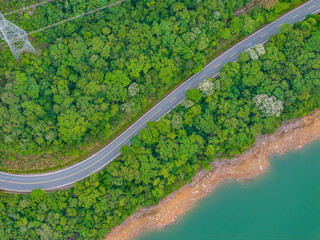 Winding mountain road by a green forest lake