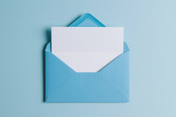 Top view of open blue envelope with blank paper sheet on isolated pastel blue background. Mockup template with copy space. Used for postal correspondence or marketing newsletter design.