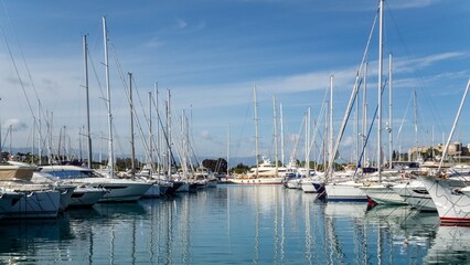 Obraz premium View of the parking of yachts in the port of a sunny morning. Reflection of yachts in water and blue sky with clouds