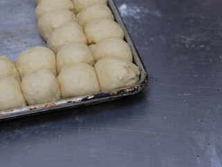 A baking sheet holds numerous unbaked dough balls, poised for baking