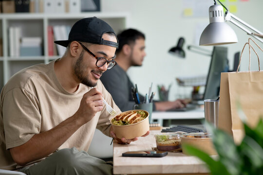Young Asian man eating healthy meal while working, Businessman having a lunch break at the office
