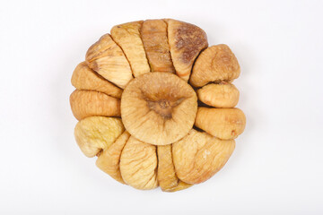 A circular arrangement of dried figs is centered on a plain light grey background, showcasing their...