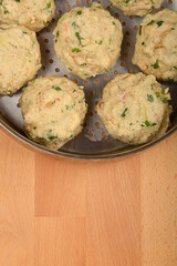 Bread dumplings with specks of herbs, placed in a metal steaming pot on a wooden surface ready for cooking