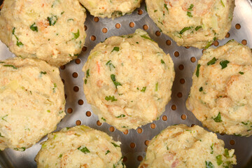 Bread dumplings with visible specks of green herbs, resting in a metal steaming pot ready for...