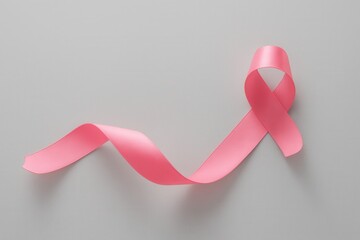 breast cancer awareness: A close-up of a pink ribbon symbolizing breast cancer awareness, laying on a light gray background, representing the fight against breast cancer and the importance of support