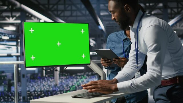 Server hub colleagues doing brainstorming, using chroma key device to review diagnostics. Employees doing maintenance tasks in data center, looking at green screen display