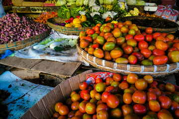 A pile of fresh red and yellow tomatoes on a container at a traditional market.