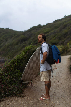 Young man carrying surfboard and walking to beach