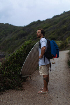 Young man carrying surfboard and walking to beach