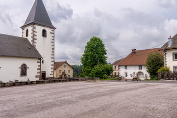 Fototapeta premium Place d'un village de montagne vosgien avec son église et son auberge : le haut du tôt