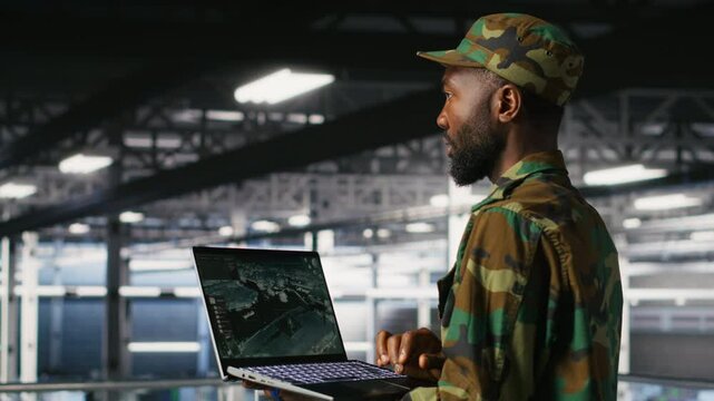 Soldier in server room uses geospatial data to support evacuation during emergency operations. Military data center personnel in uniform coordinating disaster response logistics using laptop, camera B