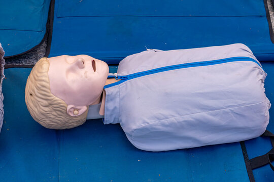 realistic CPR training mannequin lying on a blue mat, prepared for a first aid or resuscitation training session. Used for practicing life-saving techniques such as chest compressions and rescue breat