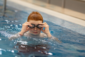 A young athlete adjusts his swimming goggles. Portrait of a swimmer putting on his goggles in the swimming pool