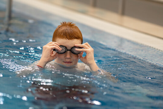 A young athlete adjusts his swimming goggles. Portrait of a swimmer putting on his goggles in the swimming pool