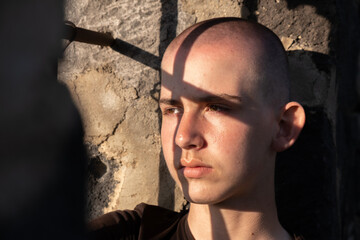 Portrait of a teenage boy in a prison cell with a sad look. Shadows from the bars fall across his face as sunlight shines through the window. A young inmate lost in thought.