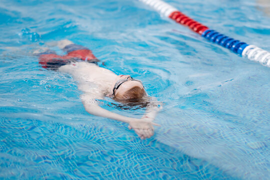 The boy in the pool will follow the coach. The child learns to swim on his back.