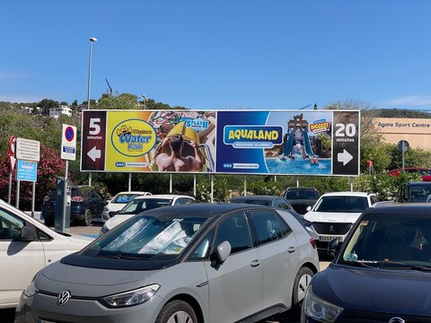 Portals Nous Spain - May 27, 2025: Aqualand water park advertisement on billboard in busy parking lot, showcasing attractions and directions for visitors to enjoy exciting activities