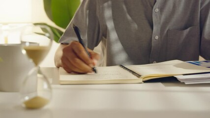 Time lapse of businessman using tablet and smartphone, taking notes and checking financial papers at office desk while working. - Powered by Adobe