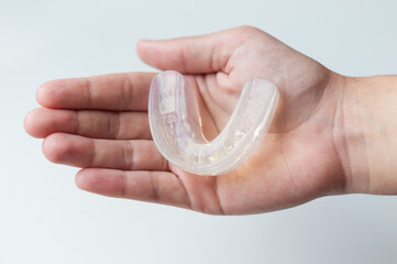 Dental silicone mouth guard for bite alignment or teeth whitening lies on a person's palm, top...