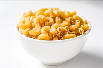 raw macaroni in a bowl isolated on white background