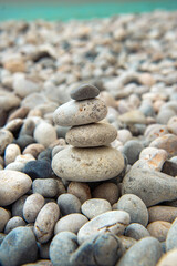 beautiful grey and white pebbles stacked on a beach and turquoise sea in background