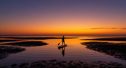 Silhouette of Woman Paddle Boarding at Sunset Calm Ocean Waters Vibrant Sky