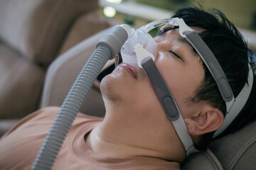 Man wearing cpap machine while lying in electric massage chair