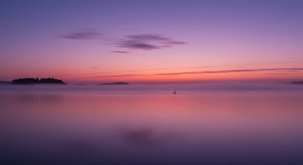 Serene Sunset over Misty Lake with Silhouetted Islands and Calm Waters
