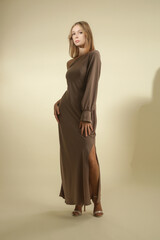 Naklejka premium Serie of studio photos of female model wearing beige maxi silk one shoulder asymmetric dress 