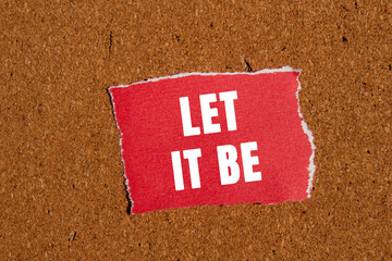 Let it be message written on ripped torn red paper piece on brown background. Conceptual let it be...