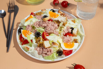 Appetizing Salad with iceberg, tuna, boiled eggs in a white plate on the table. Healthy breakfast
