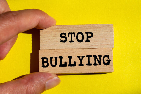 Stop bullying message written on wooden blocks on yellow background. Conceptual stop bullying symbol. Copy space.
